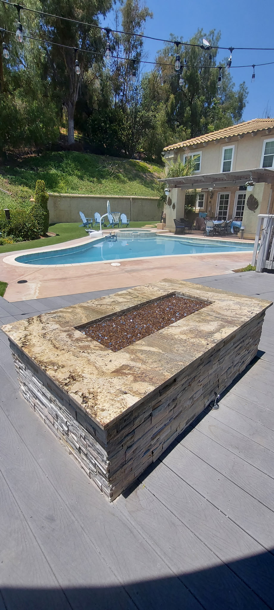 Custom stacked stone fire pit with pool in background